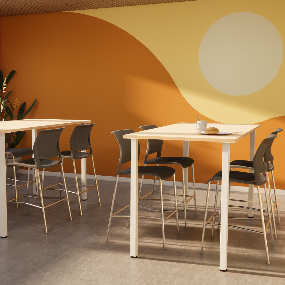 Modern cafe setting with high tables and gray chairs on a light floor. An orange wall features a sun-like design, creating a warm, inviting ambiance.