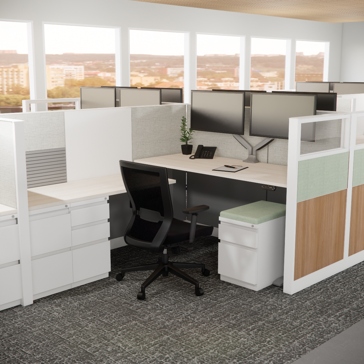 Modern office cubicle with dual monitors on a light wood desk, black chair, phone, and plant. Neutral tones, large windows, city view.