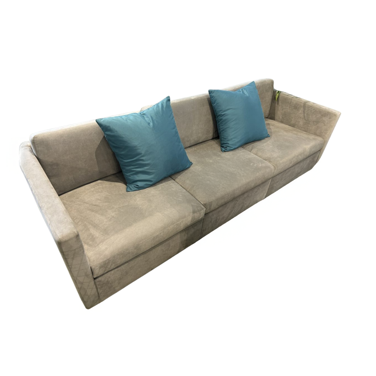 A beige upholstered sofa with two blue square cushions sits against a white background. The scene conveys simplicity and comfort.