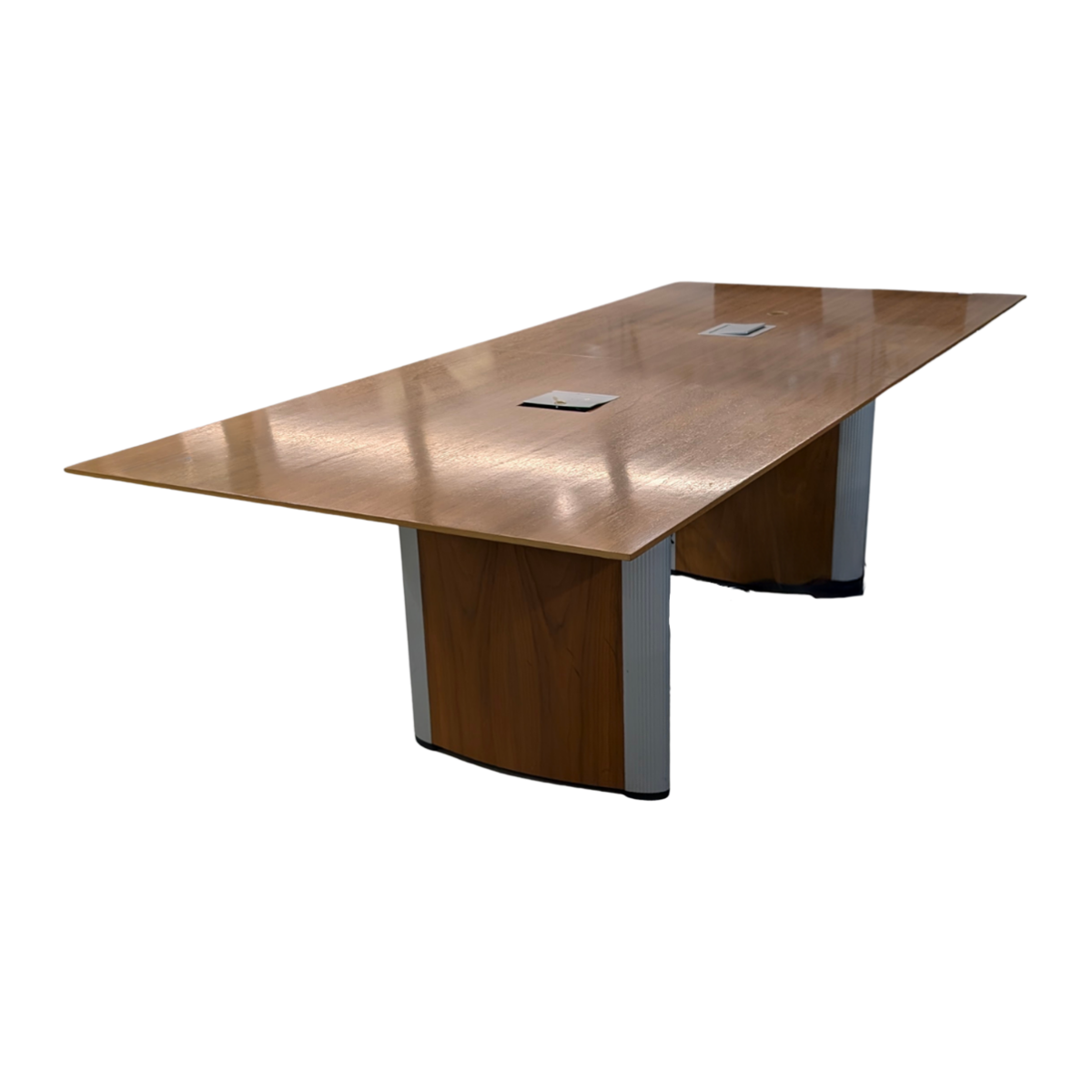 A long, rectangular wooden conference table with a smooth, polished surface and sturdy supports. It features two built-in cable management ports.