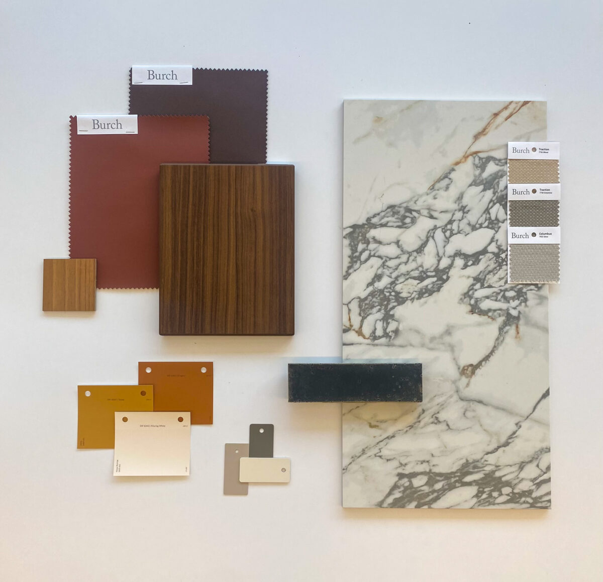 A collection of design samples on a white surface, featuring marble, wood, fabric swatches, and color chips in warm tones, conveying an elegant and stylish mood.