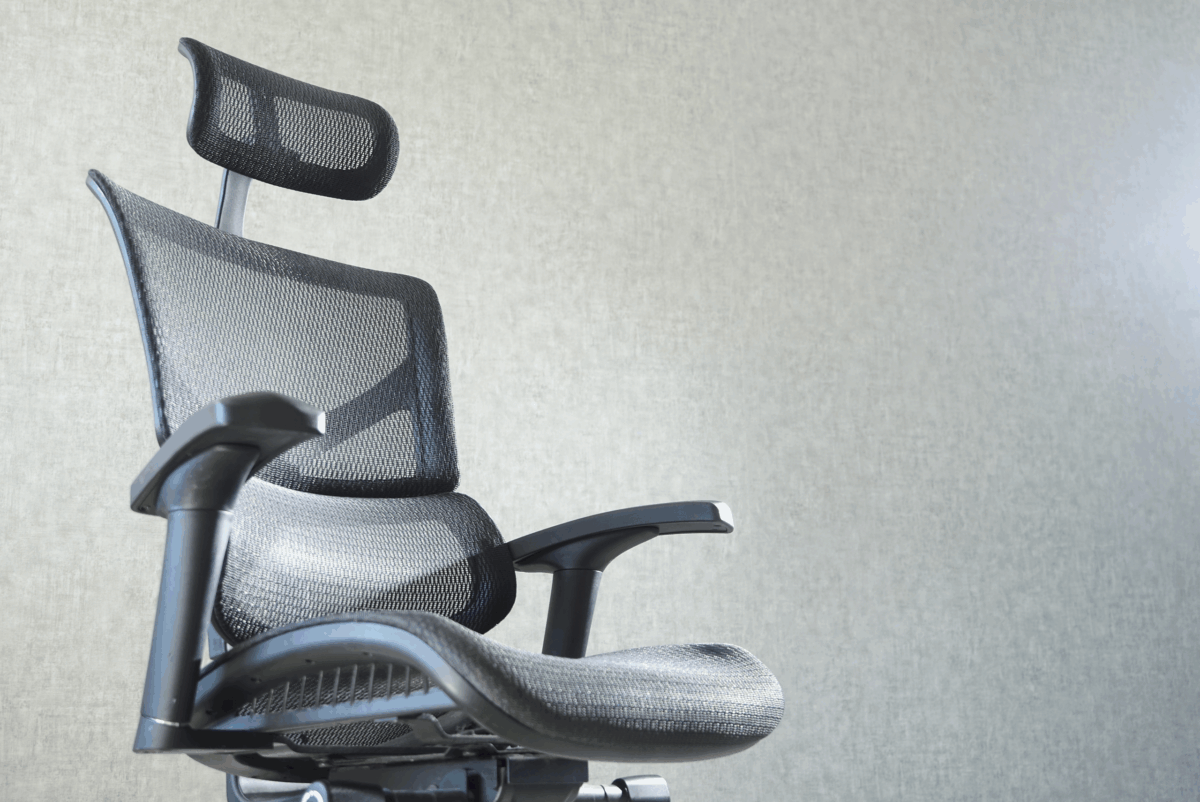 Ergonomic office chair with mesh back and headrest against a light gray wall. The scene conveys a modern, professional atmosphere.