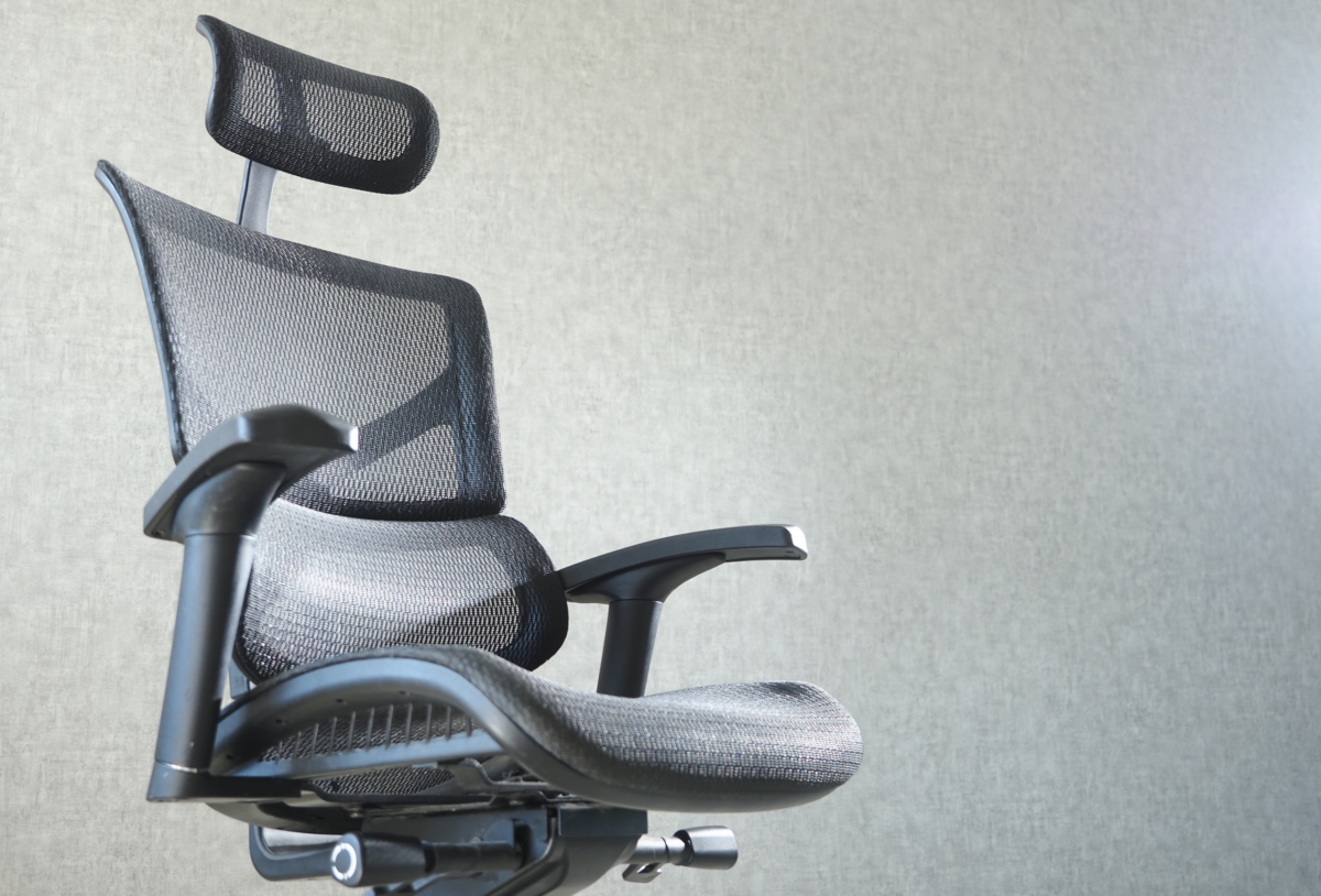 Ergonomic office chair with mesh back and headrest against a light gray wall. The scene conveys a modern, professional atmosphere.