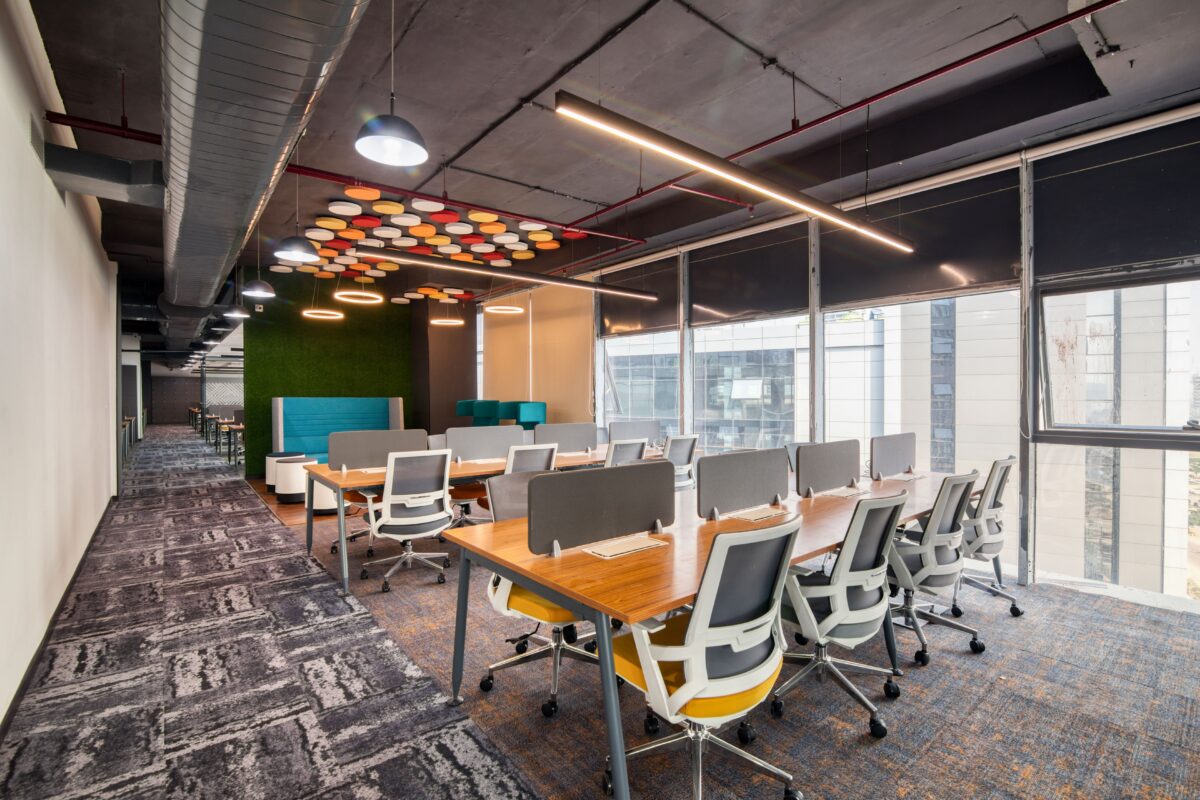 Modern open-plan office with benching workstations, ergonomic office chairs, acoustic privacy screens, collaborative seating, and contemporary commercial lighting.